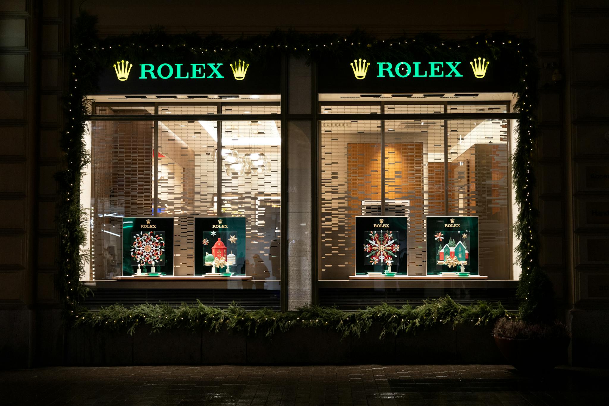 Services Nighttime view of a Rolex store with festive Christmas decorations and lights.